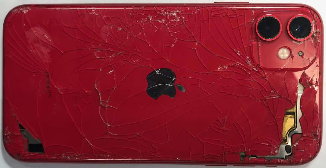 замена заднего стекла iPhone: разбитая задняя панель красного iPhone с трещинами и сколами